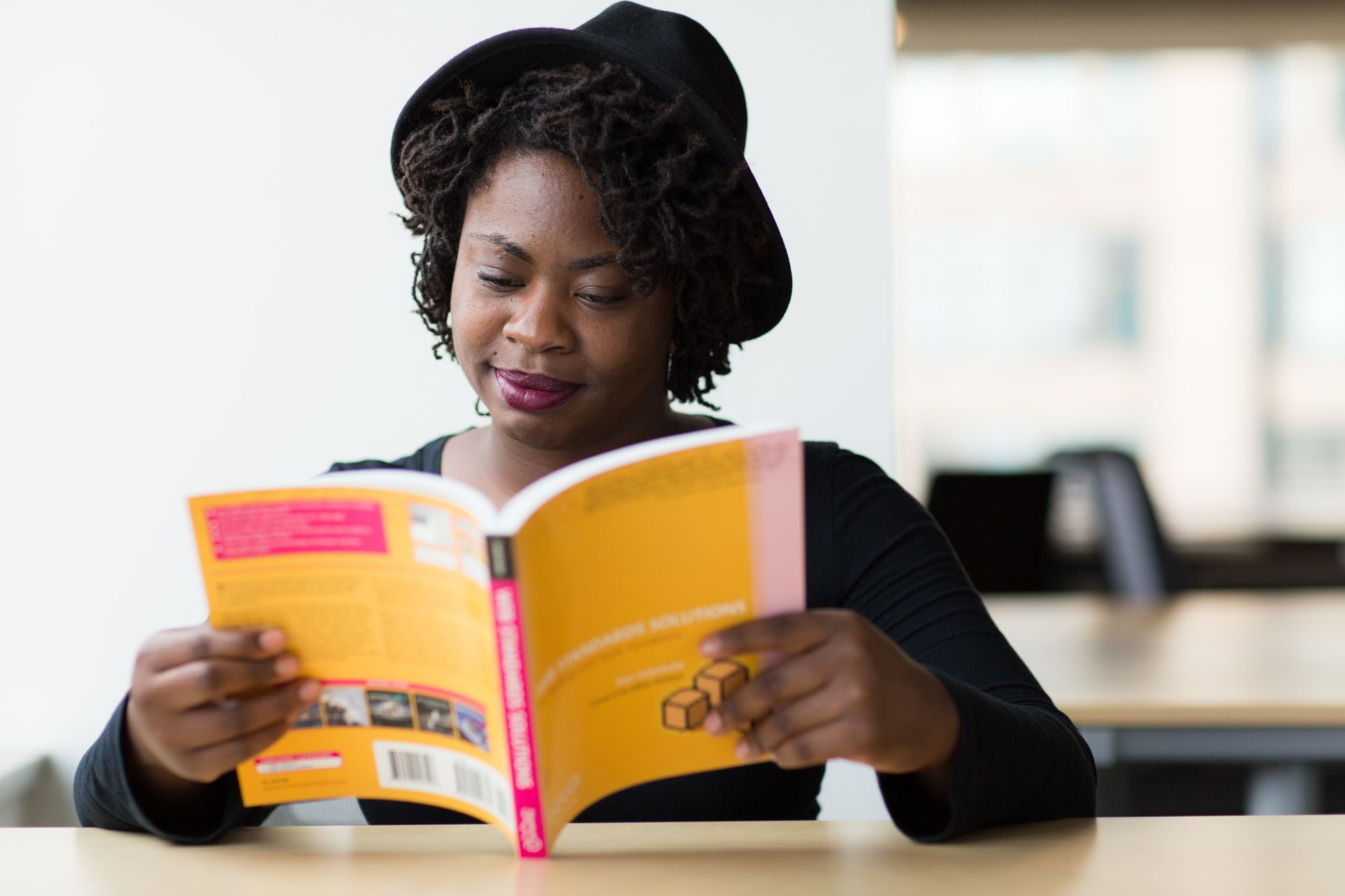 Lady with hat reading book studying for test
