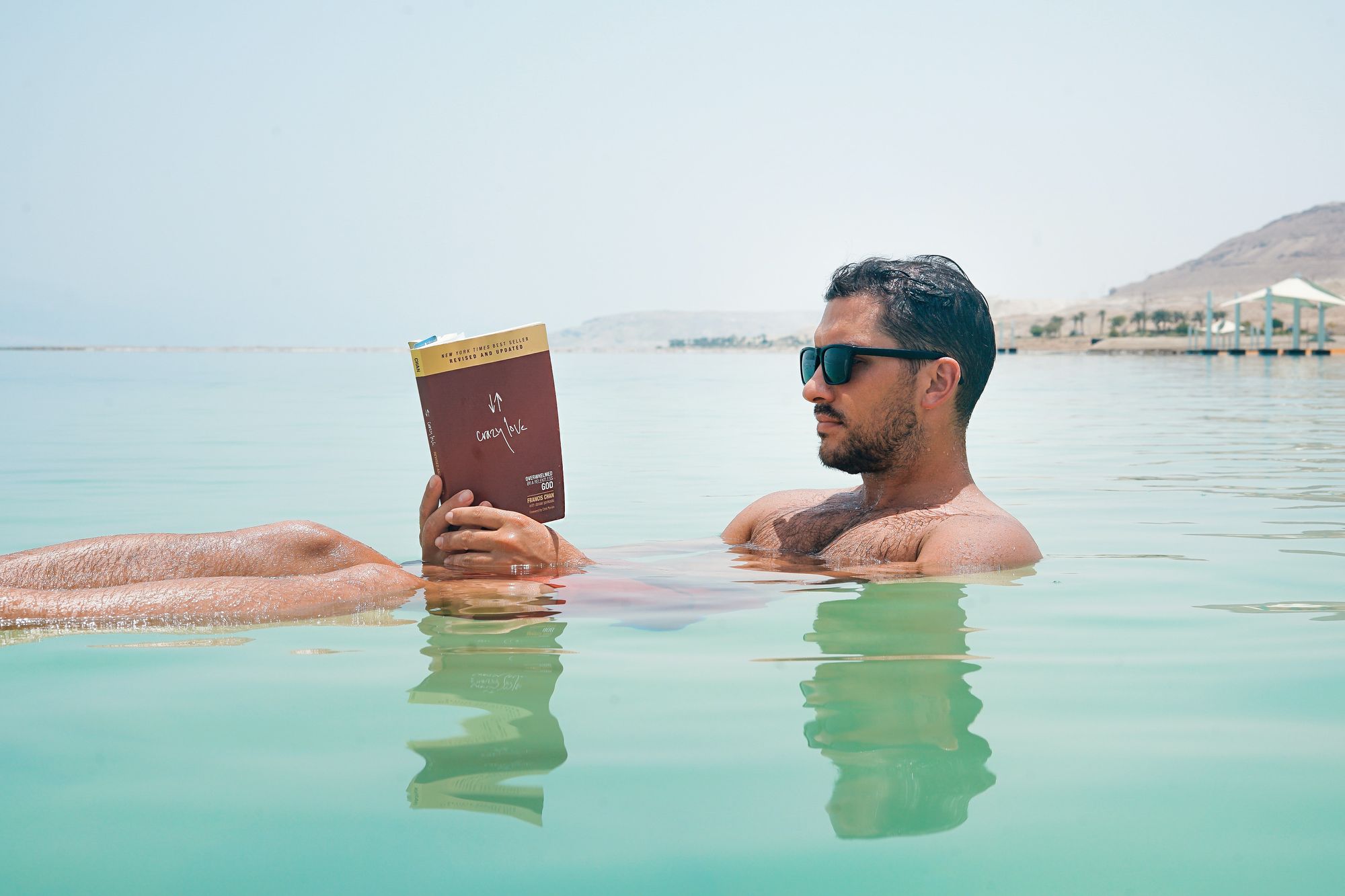 Man floating in the water with a book