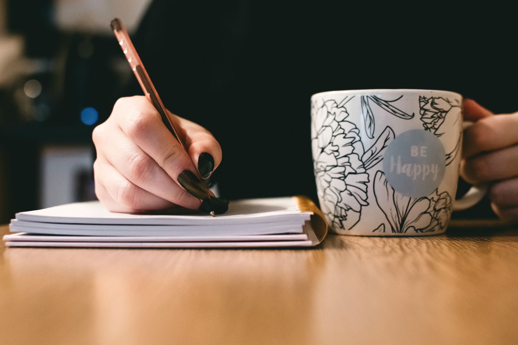 Woman writing in notebook with mug learning a new language
