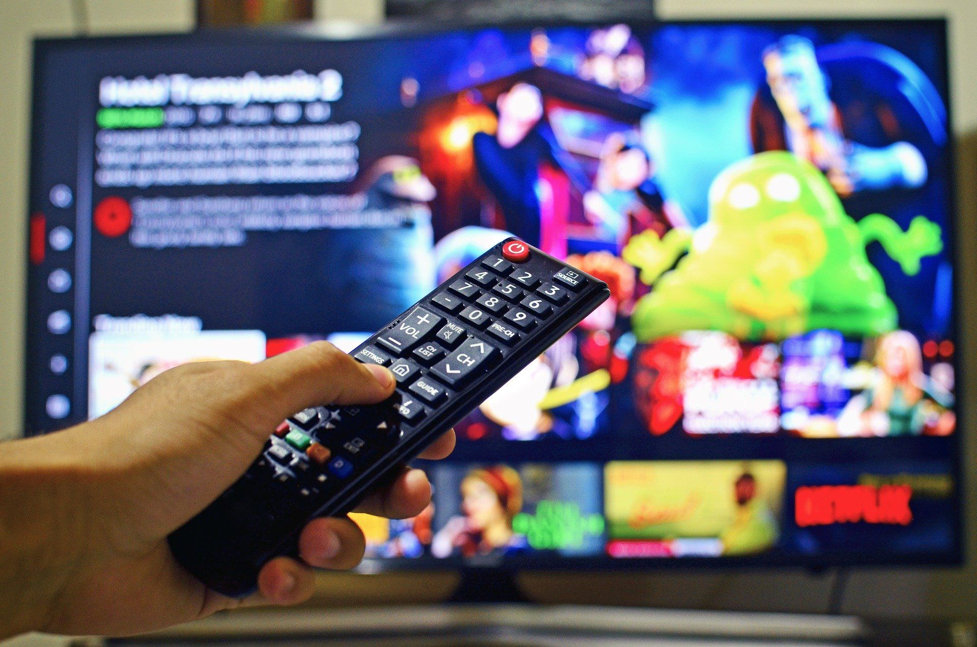 TV and hand holding a remote control