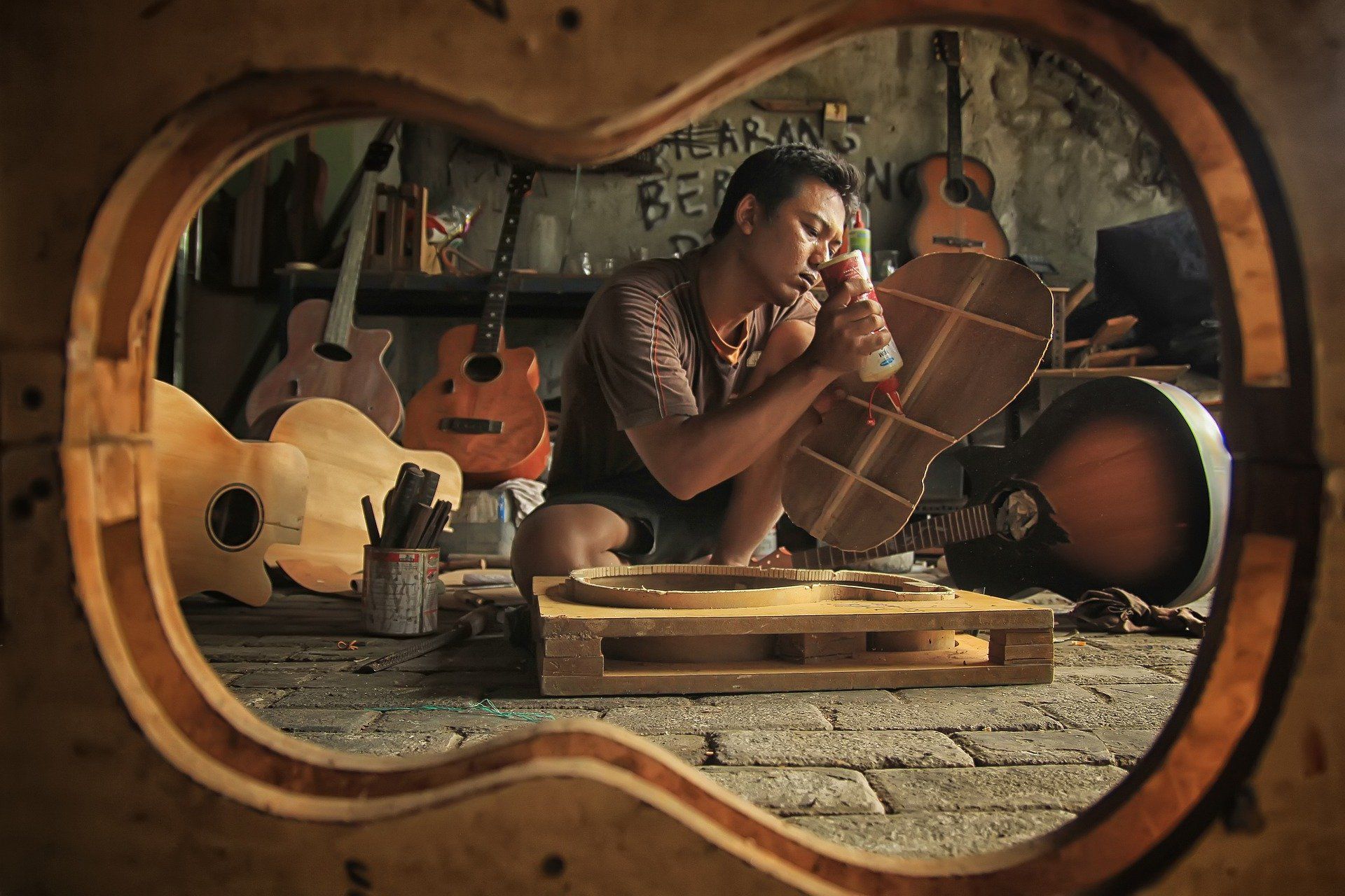 Man putting a guitar together in a workshop
