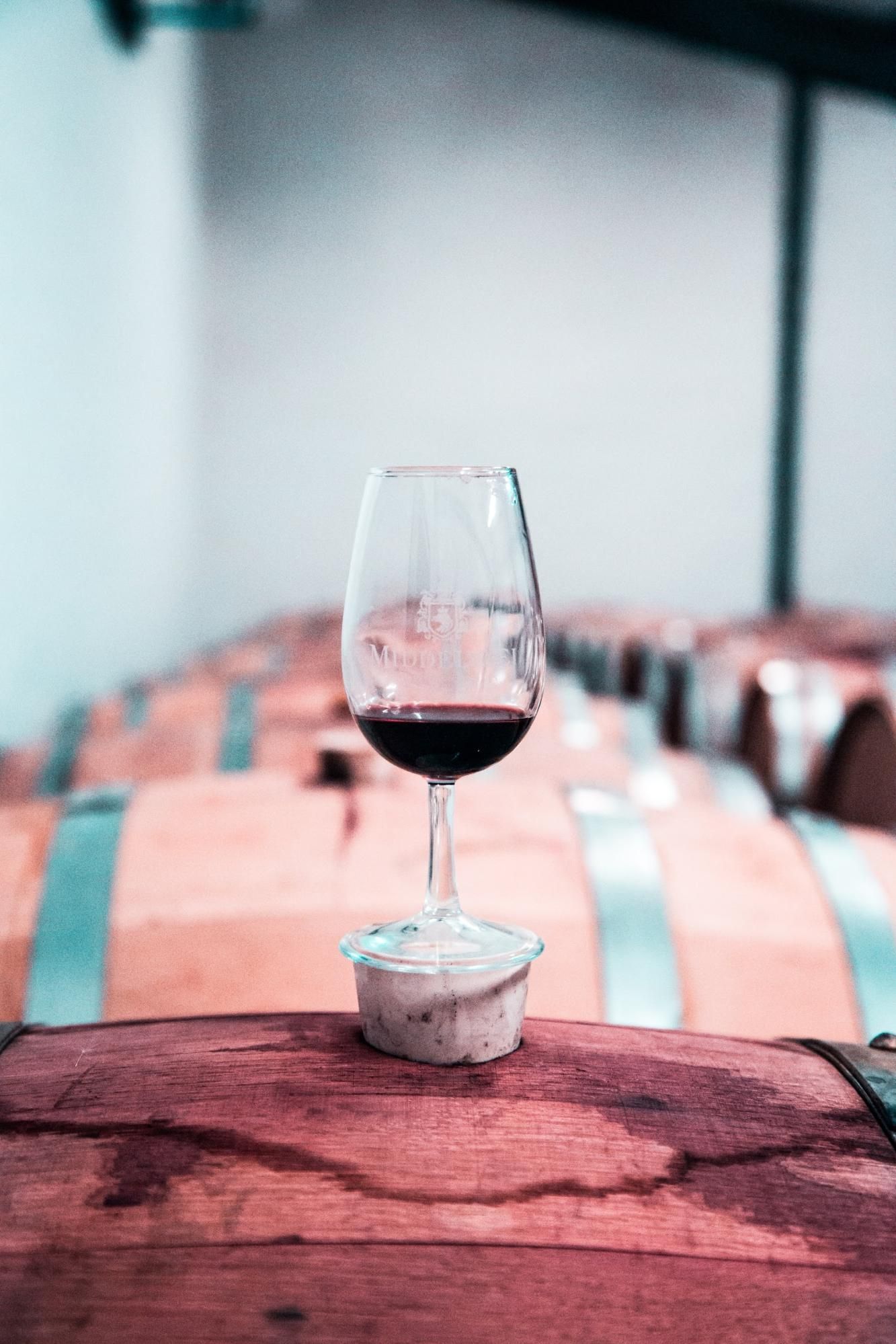 Red wine glass standing on a barrell