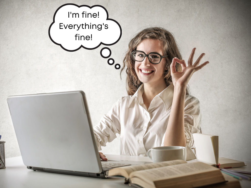 Woman using computer in white shirt with thought bubble that says "I'm fine! Everything's fine!" and an ok symbol on her hand.