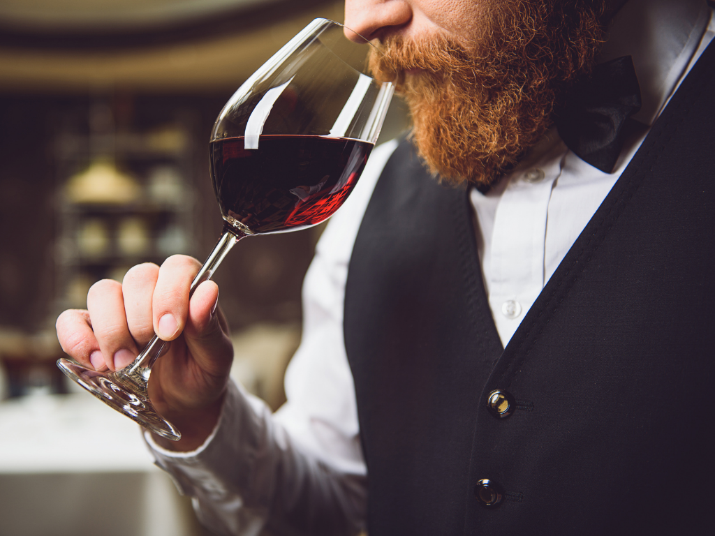 Male sommelier with red beard smelling a glass of red wine