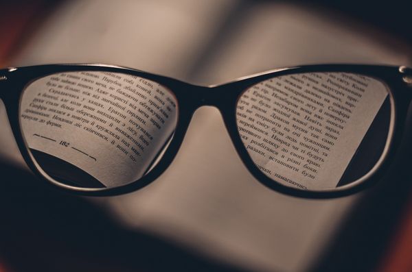 Brille, die die Wörter in einem verschwommenen Buch deutlich anzeigt, schlechtes Sehen, das mit einer Brille behoben wird