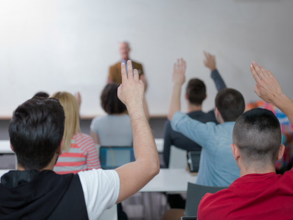 Class of students with their hands raised